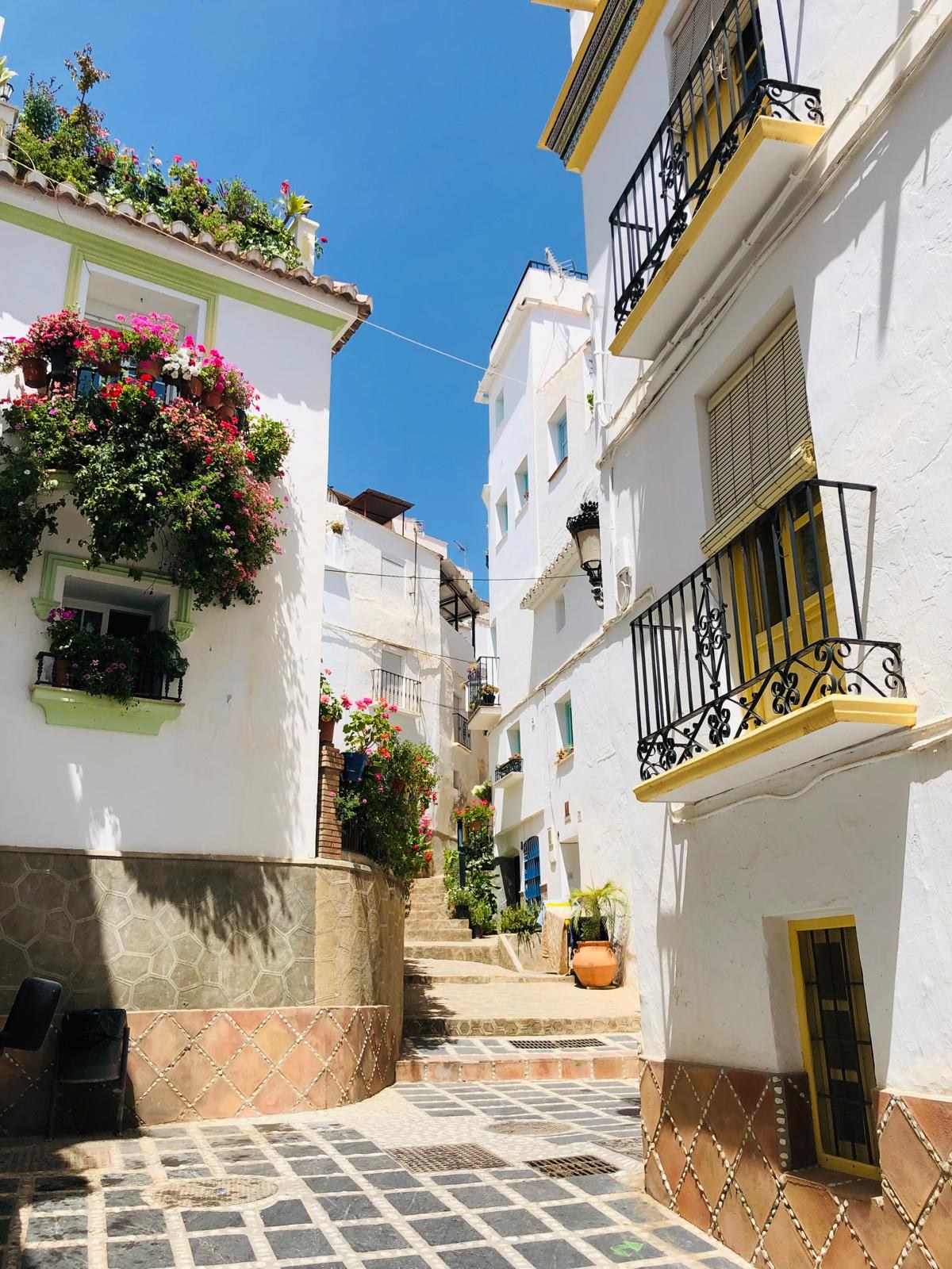 Flower-filled balconies above a stepped lane in Cómpeta