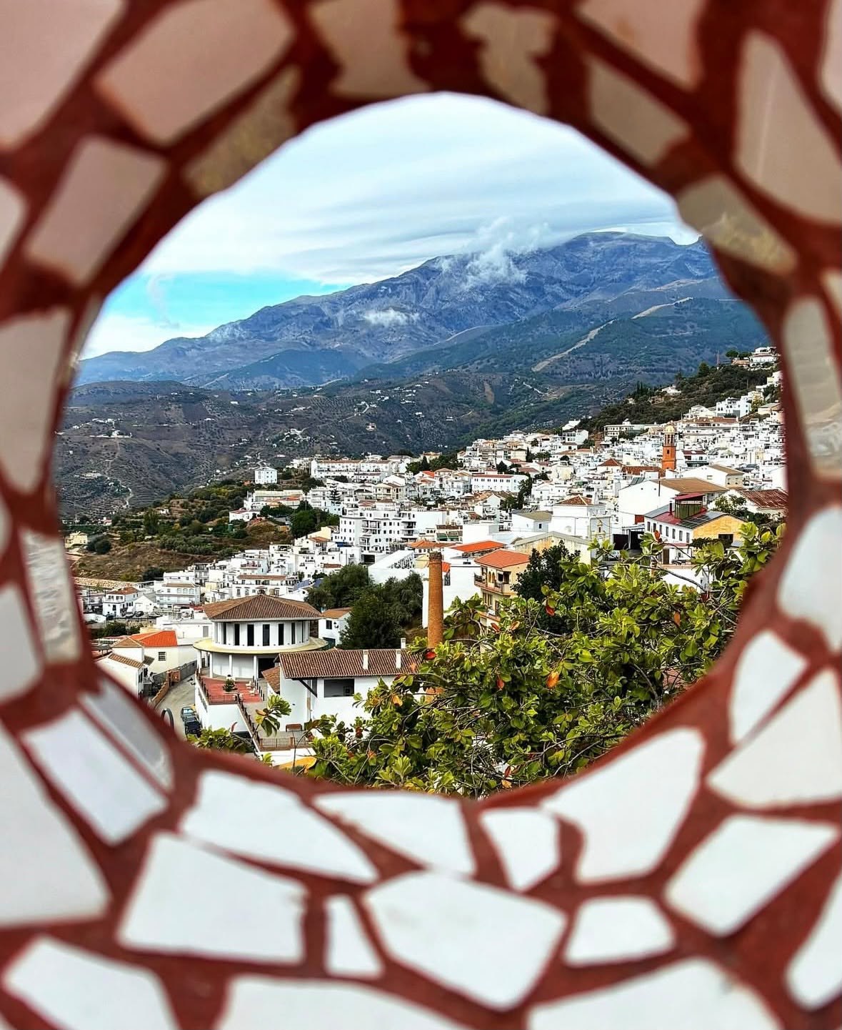 Cómpeta and the mountains framed by a decorative mosaic opening